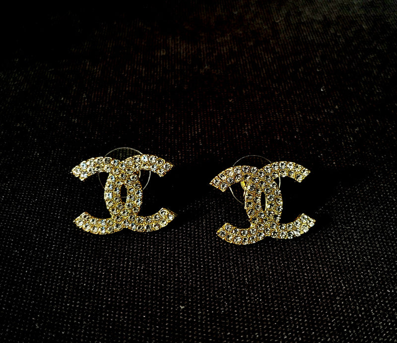 Gold CC earrings on a black background