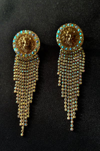 Pair of gold earrings with lion emblem and dangling rhinestone tassels on a black background