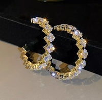 A pair of gold-colored mini bling hoop earrings covered in square cz stones.